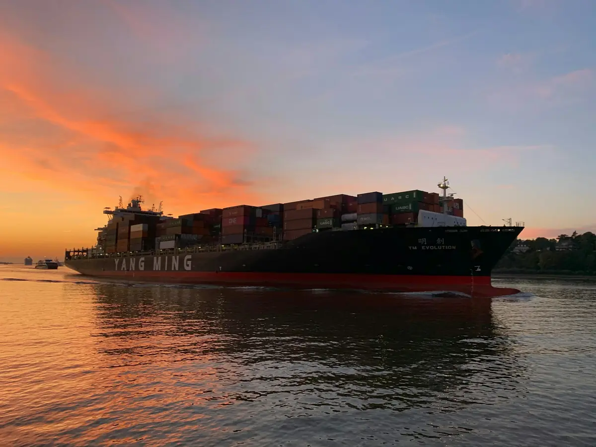 Container ship sailing into an orange sunset